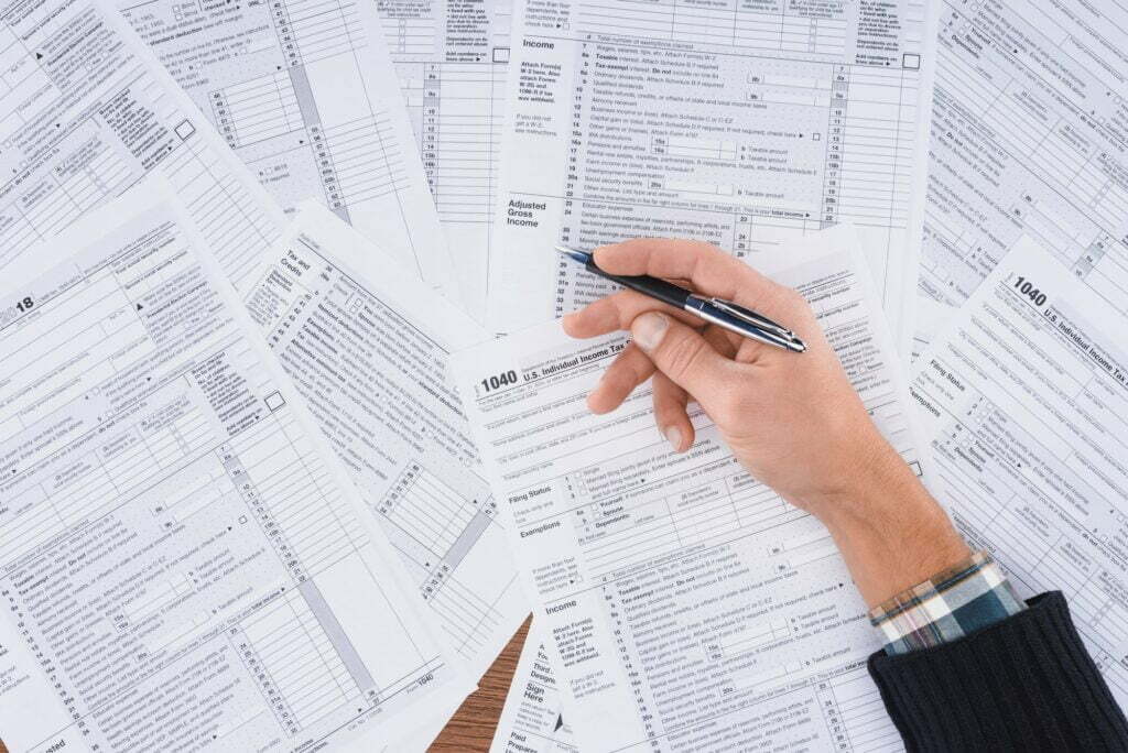 partial view of man holding pen and filling tax forms with copy space